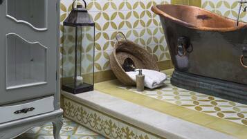 Un baño con bañera, espejo, lámpara y un tapete decorativo.