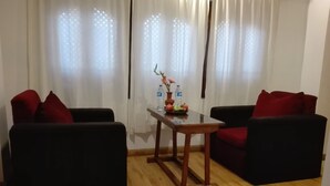 A room with two black sofas, a small wooden table, and a vase with flowers. - Sunny Guest House and Cafe (Bhaktapur)