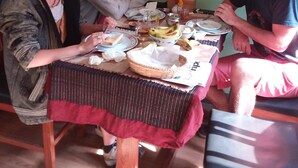 A dining table with food and drinks, surrounded by four people. - Mountain Guest House (Bhaktapur)