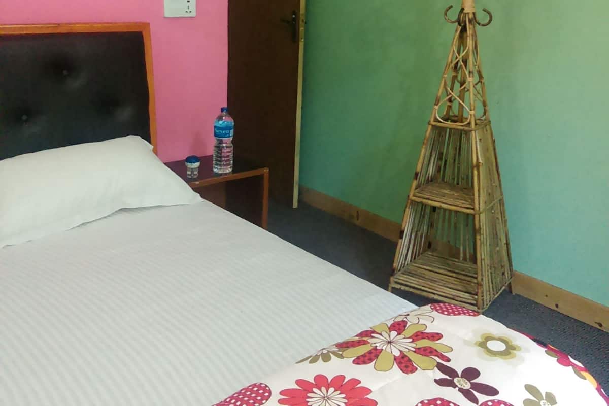 A bedroom with a bed, a water bottle, and a wooden drying rack.