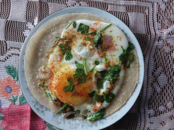 Un plato de comida con un huevo escalfado, cilantro y especias sobre un mantel estampado.