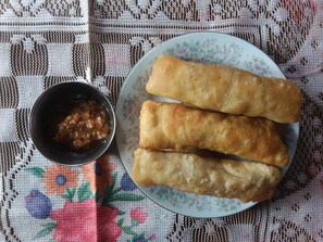 A plate with three fried items and a small bowl of sauce.