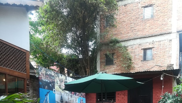 An outdoor seating area with tables and chairs, surrounded by potted plants and a mural. - Mountain Guest House (Bhaktapur)