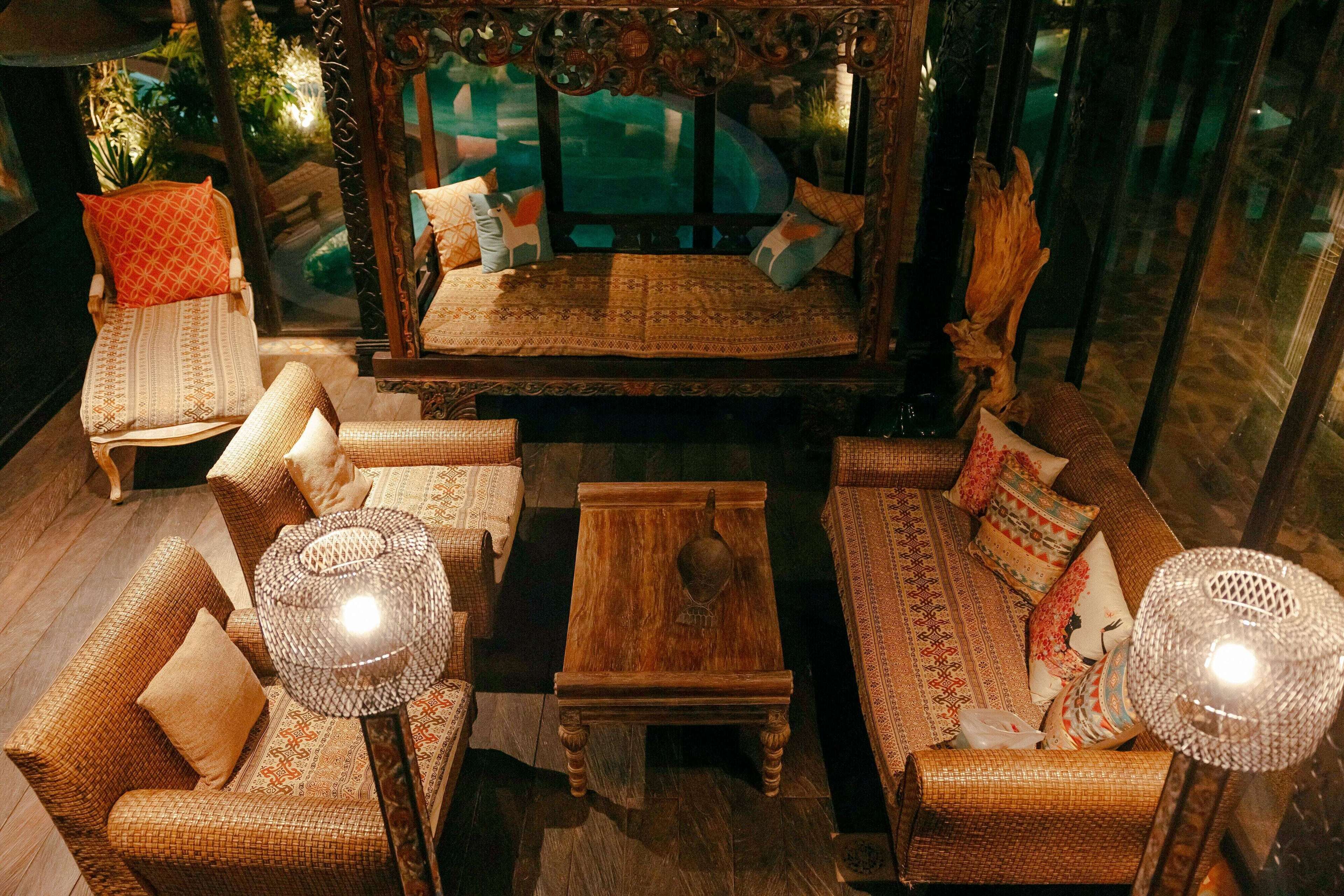 A cozy lounge area with wicker furniture, a wooden coffee table, and a mirror with a decorative frame.