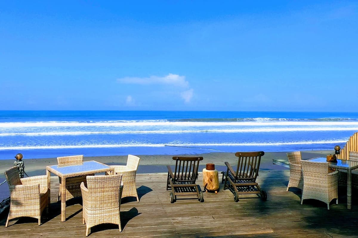 A wooden deck with wicker furniture overlooking the ocean.