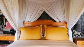 A bed with a wooden headboard, white curtains, and two yellow pillows.