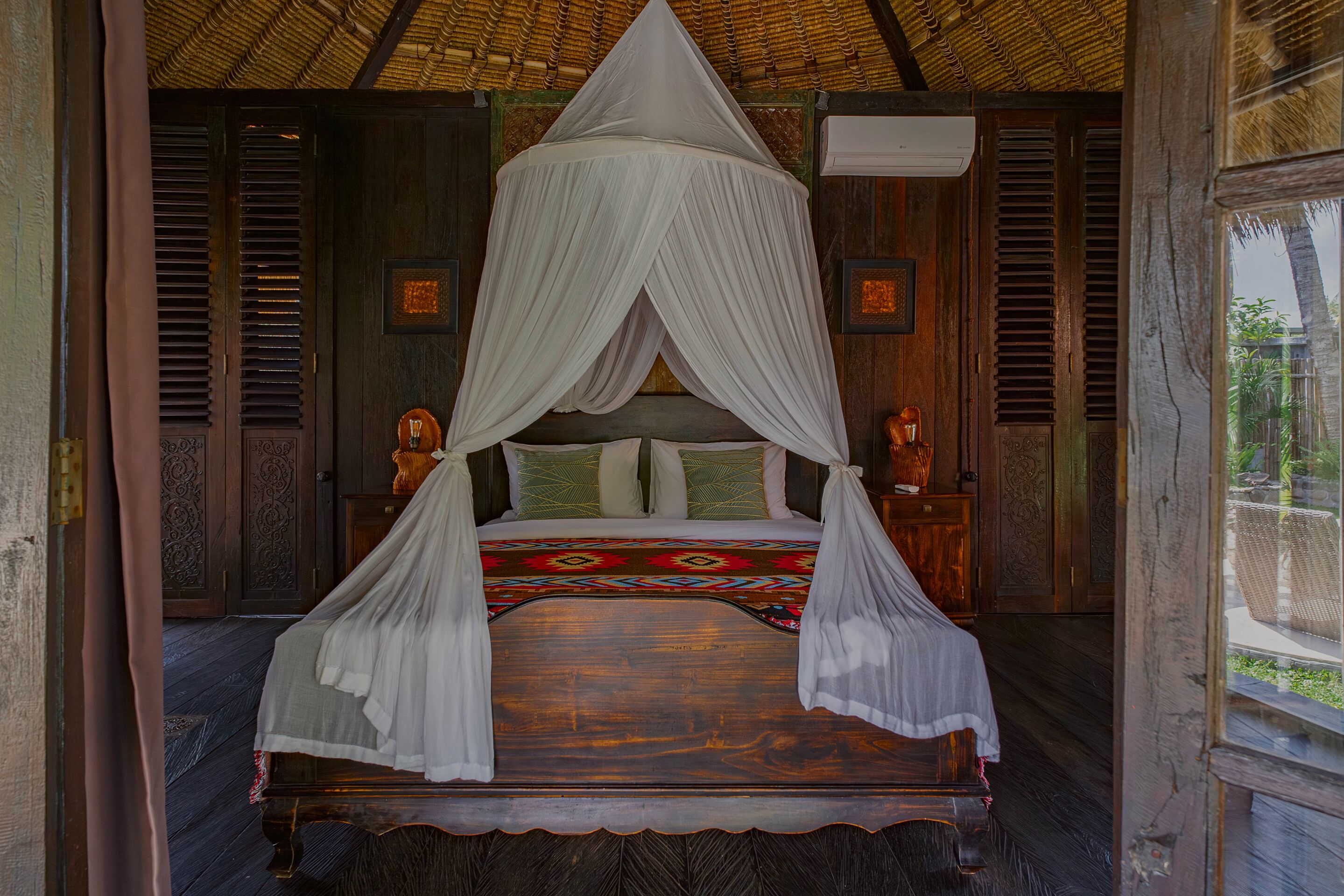 A bed with a canopy, wooden walls, and a window with a view of greenery.