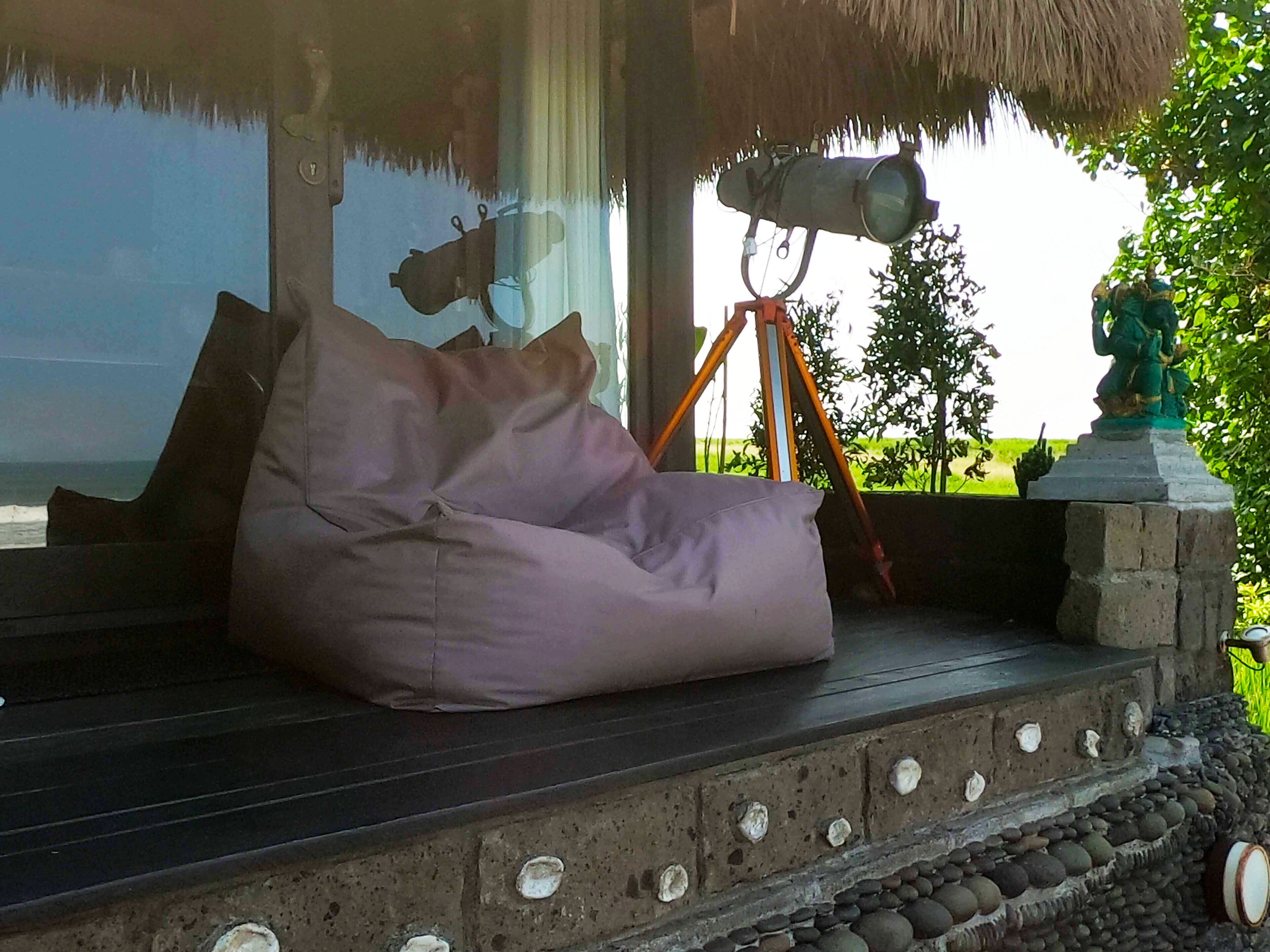 A beachside seating area with a bean bag, a tripod, and a statue.
