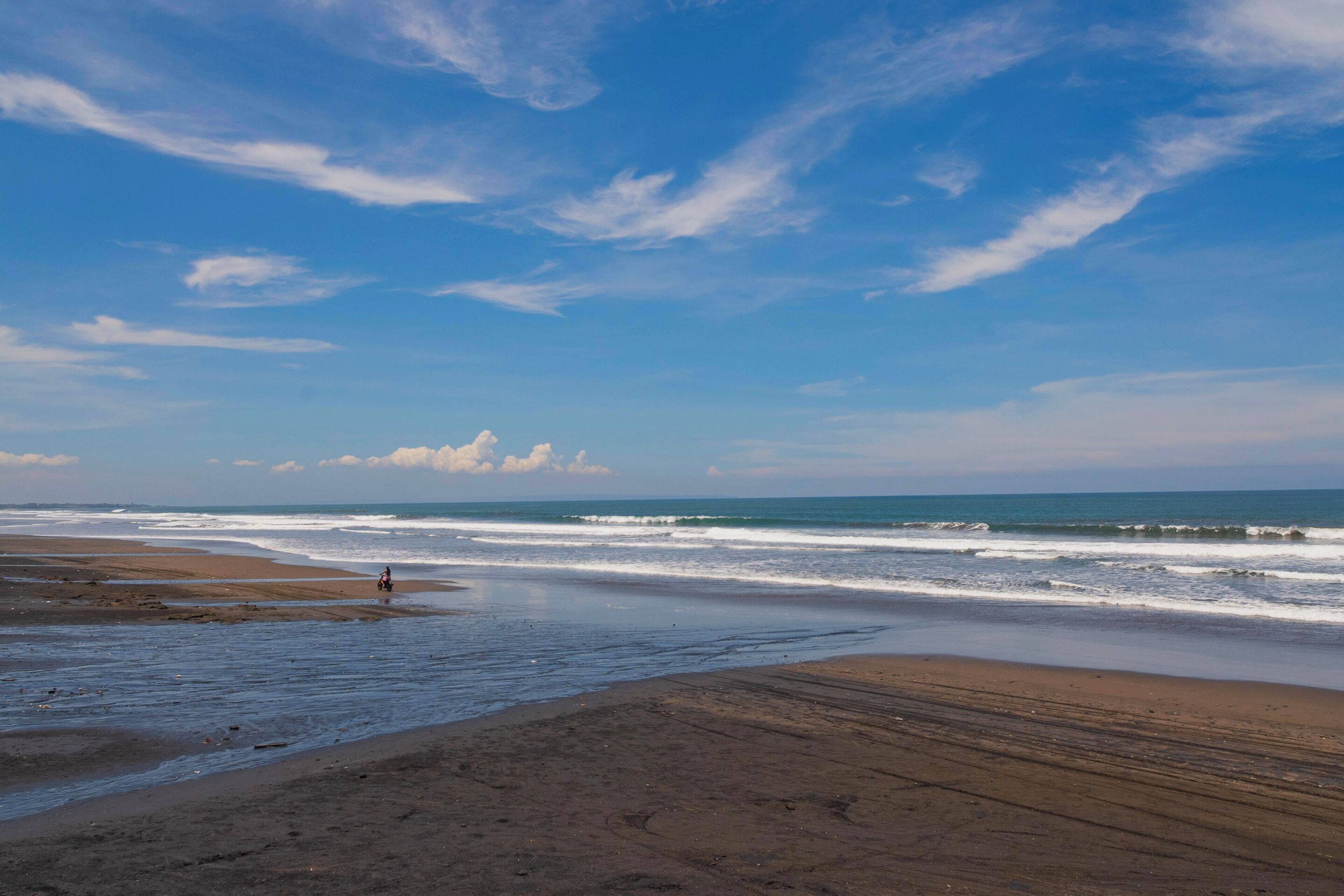 A beach with wide sandy areas and gentle waves.