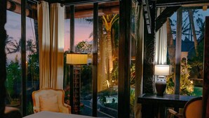 A hotel room with a bed, two chairs, a desk, and a lamp. - Most Exotic Beachfront Villa Keong (Tabanan)