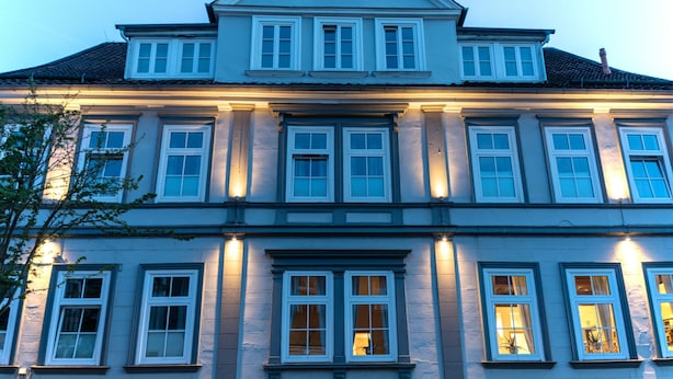 En stor, flerlækket bygning med symmetrisk arkitektur, jævnt fordelte vinduer og en central indgang.