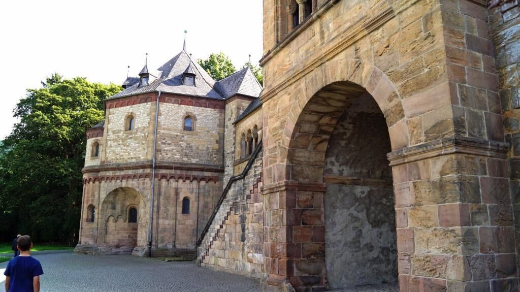 A historic stone building with a prominent archway and a tower with a conical roof.