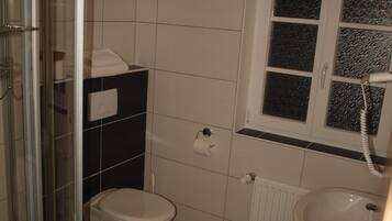 A bathroom with a toilet, sink, and glass shower enclosure.