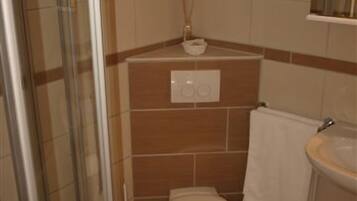 Un baño con inodoro, lavamanos y cabina de ducha de vidrio.