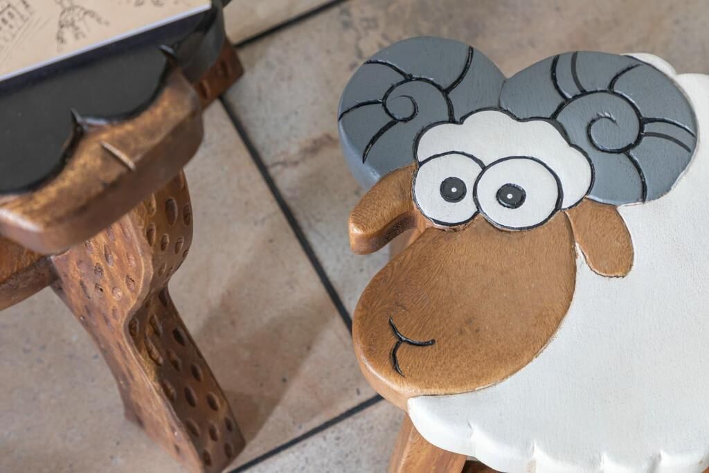 A wooden chair with a decorative sheep head.