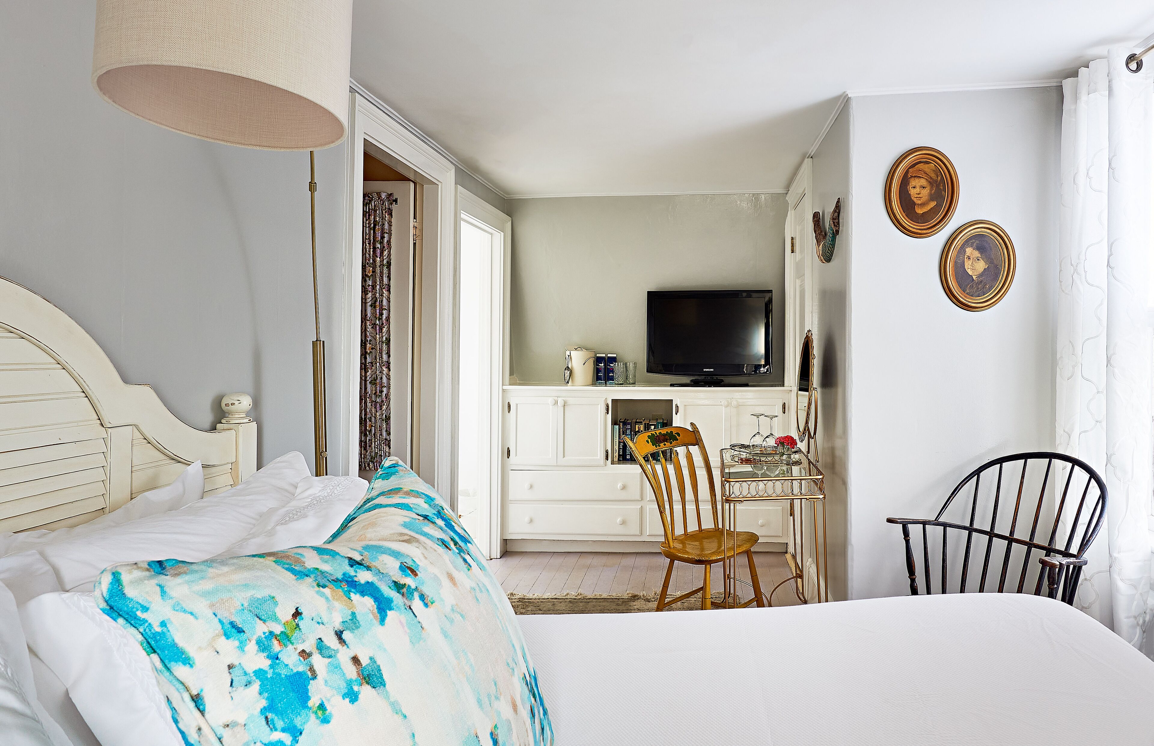 A bedroom with a bed, a desk, a chair, and a television.