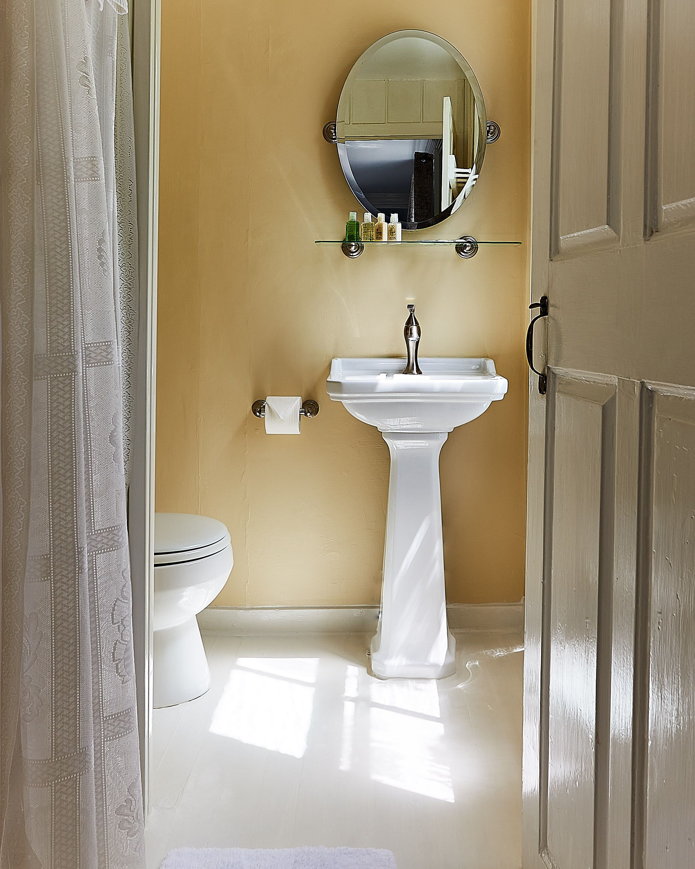 Une salle de bain avec un lavabo blanc, des toilettes et un miroir au-dessus du lavabo.