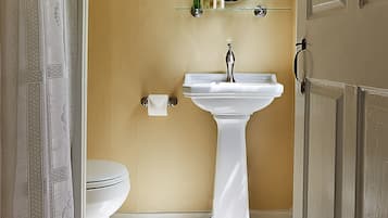 Une salle de bain avec un lavabo blanc, des toilettes et un miroir au-dessus du lavabo.