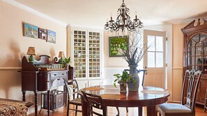 A dining room with a wooden table, chairs, a chandelier, and a cabinet with dishes. - Cliff Lodge (Nantucket)