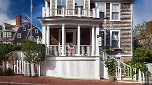 A multi-story building with a balcony and a porch, featuring a flag and a sign indicating a lodge. - Cliff Lodge (Nantucket)