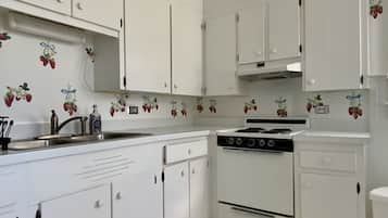 A kitchen with white cabinets, a stove, and a sink.