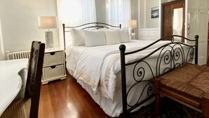 A bedroom with a bed, bedside tables, a chair, a dresser, and a mirror. - Cliff Lodge (Nantucket)