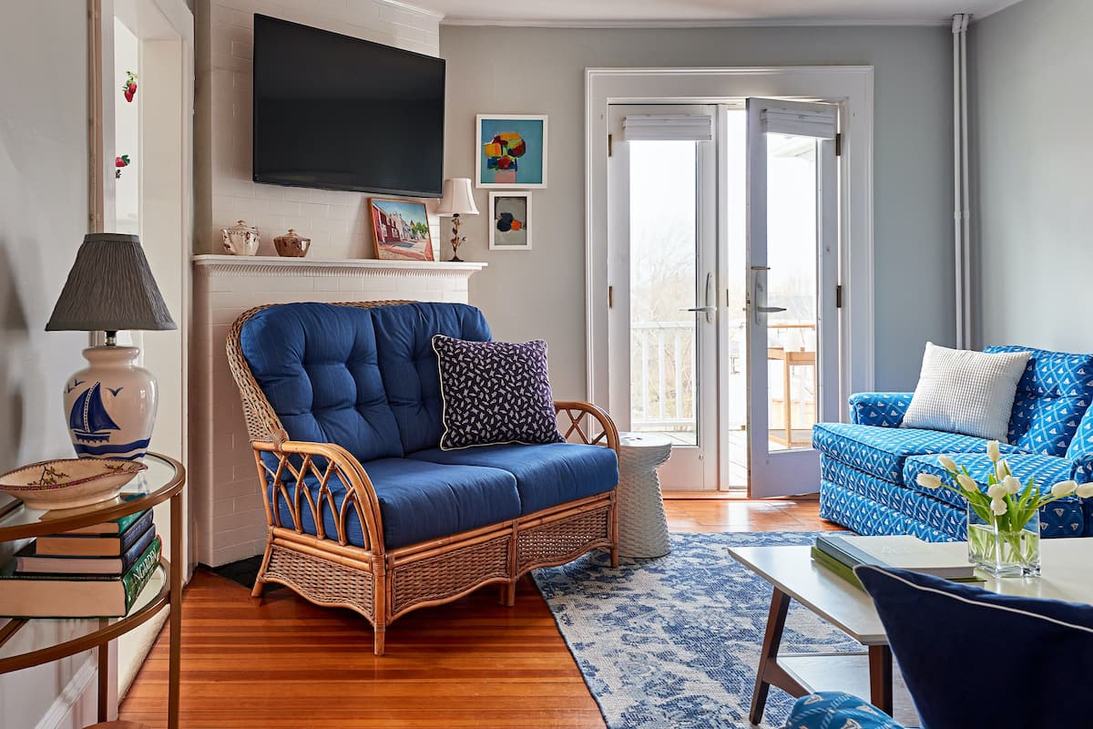 A living room with a blue sofa, wicker armchair, and a matching blue patterned sofa.