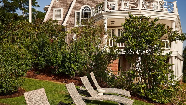 A large house with a balcony and a flagpole with flags. - Cliff Lodge (Nantucket)