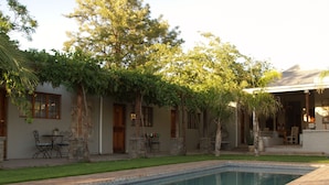 A pool area with a stone border, a patio with outdoor furniture, and a building with multiple doors and windows.