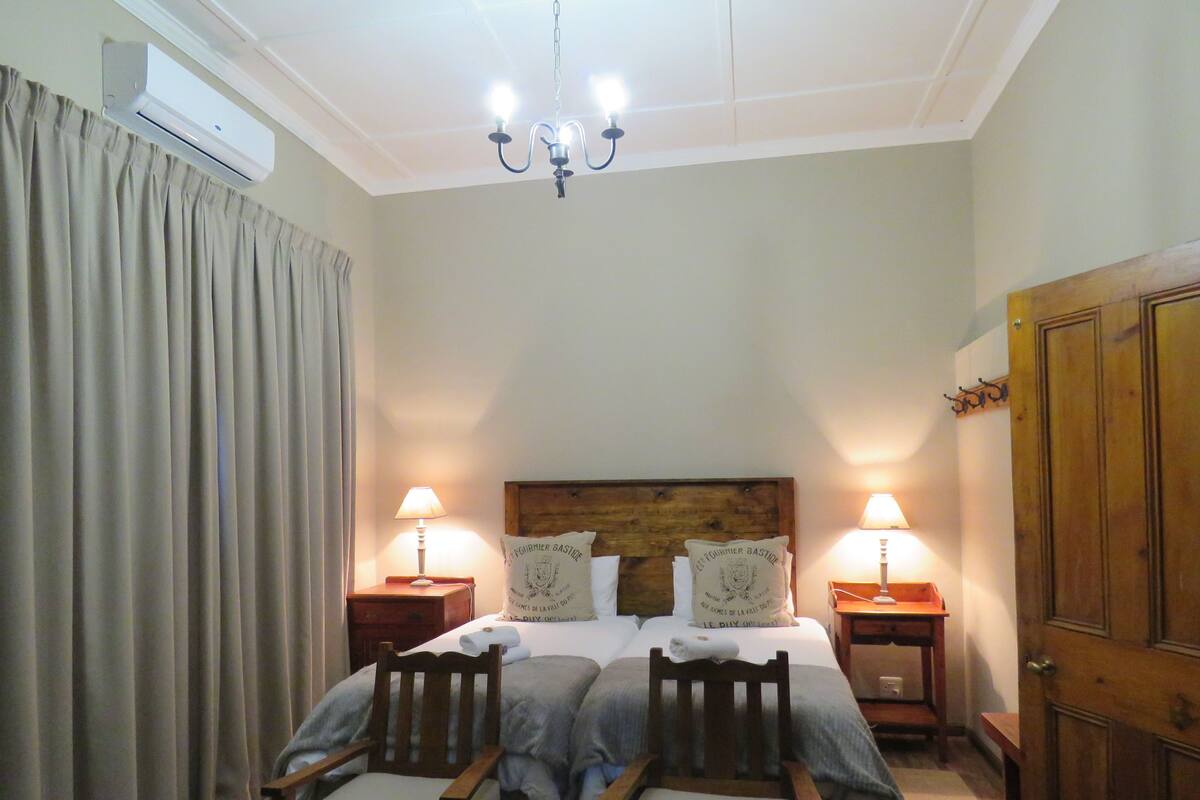 Ein Schlafzimmer mit einem Doppelbett, zwei Nachttischen mit Lampen, einem Holz-Bettkopfteil, einem Holzschrank und einer Chandelier.