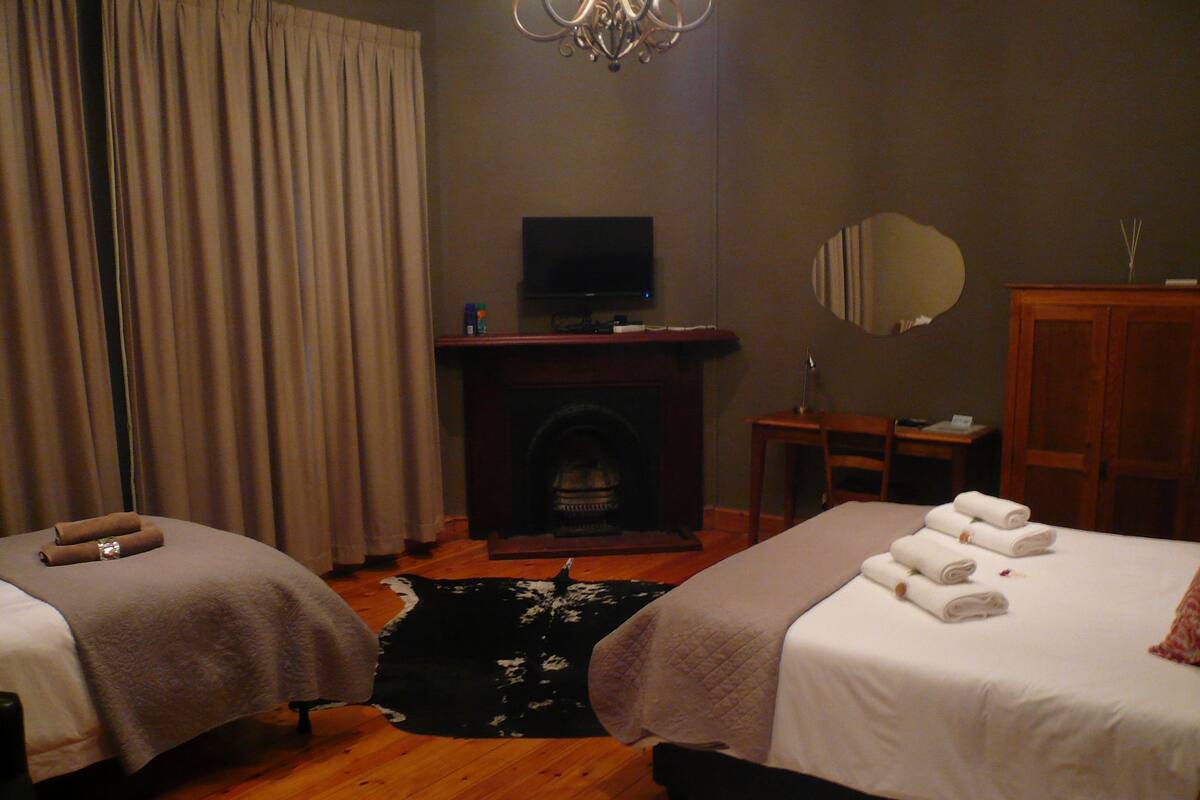 Ein Hotelzimmer mit zwei Betten, einem Fernseher, einem Kamin, einem Spiegel und Holzboden.