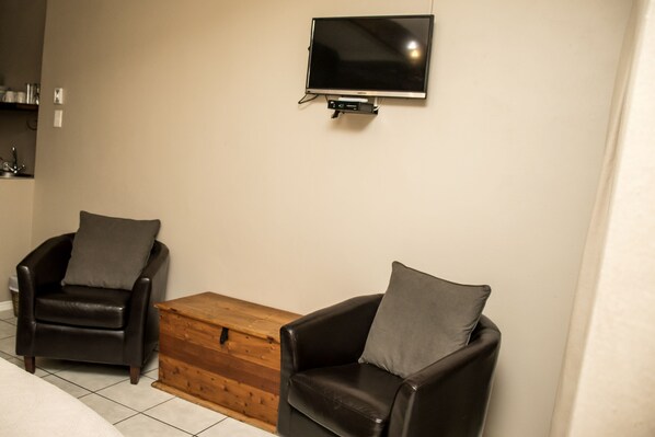 Una habitación con dos sillones de cuero, una mesa de centro de madera y un televisor de pantalla plana montado en la pared.