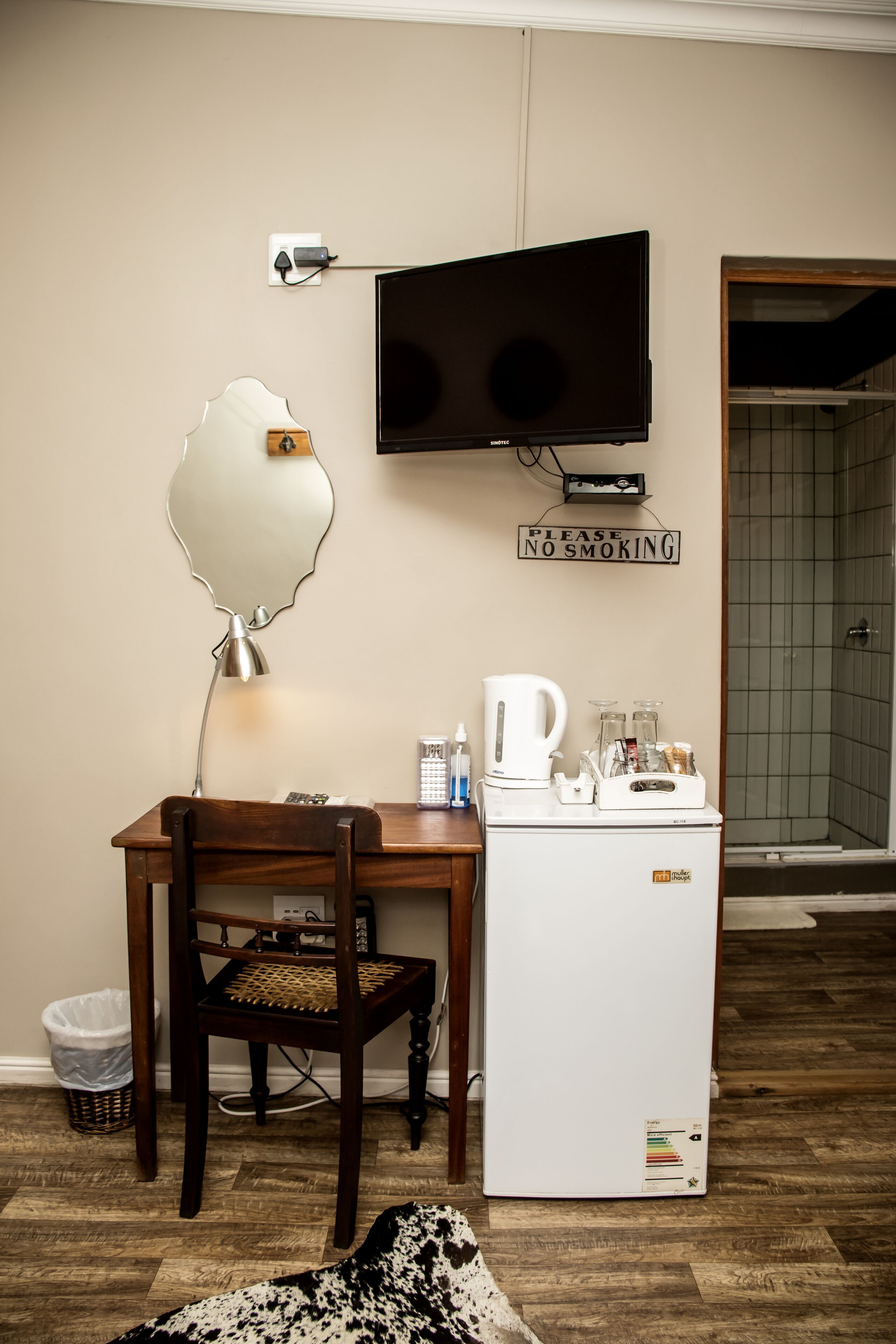Une petite kitchenette équipée d’un réfrigérateur, d’un four à micro-ondes et d’une machine à café. Un téléviseur est fixé au mur, et un panneau indique : « Merci de ne pas fumer. »