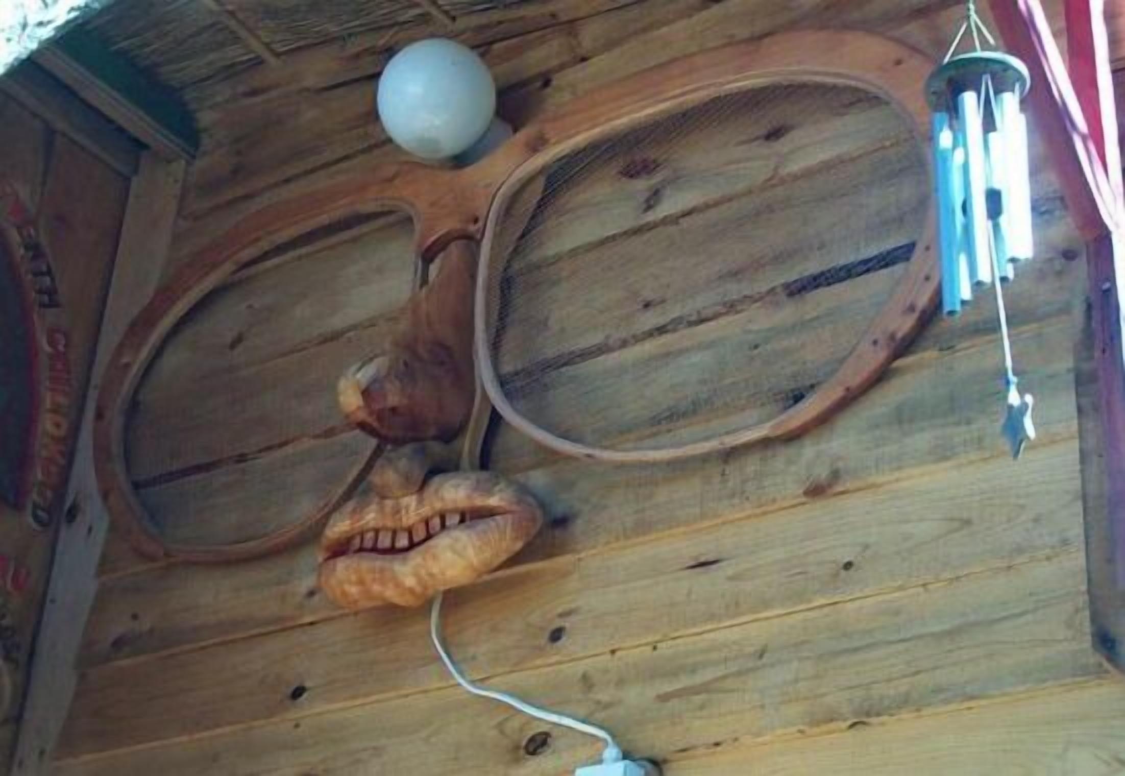A wooden ceiling with a unique design, including circular cutouts and a hanging wind chime.