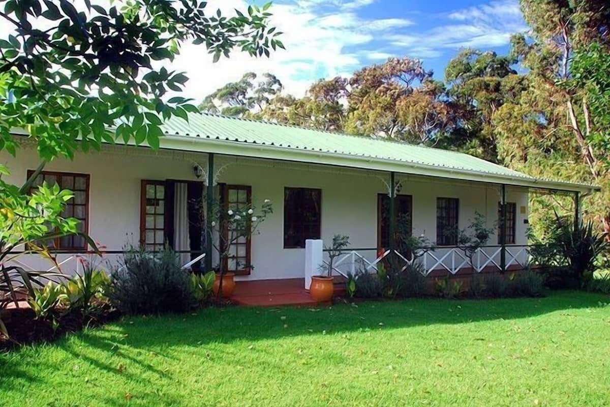 Une maison à deux étages avec un toit végétalisé, une véranda et une pelouse bien entretenue.