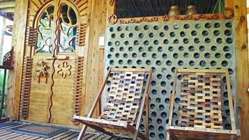 A wooden structure with a decorative door, a wall with circular holes, and two wooden chairs.