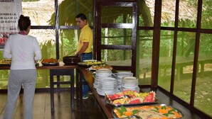 Montaje de bufé con diferentes alimentos y una persona sirviendo.