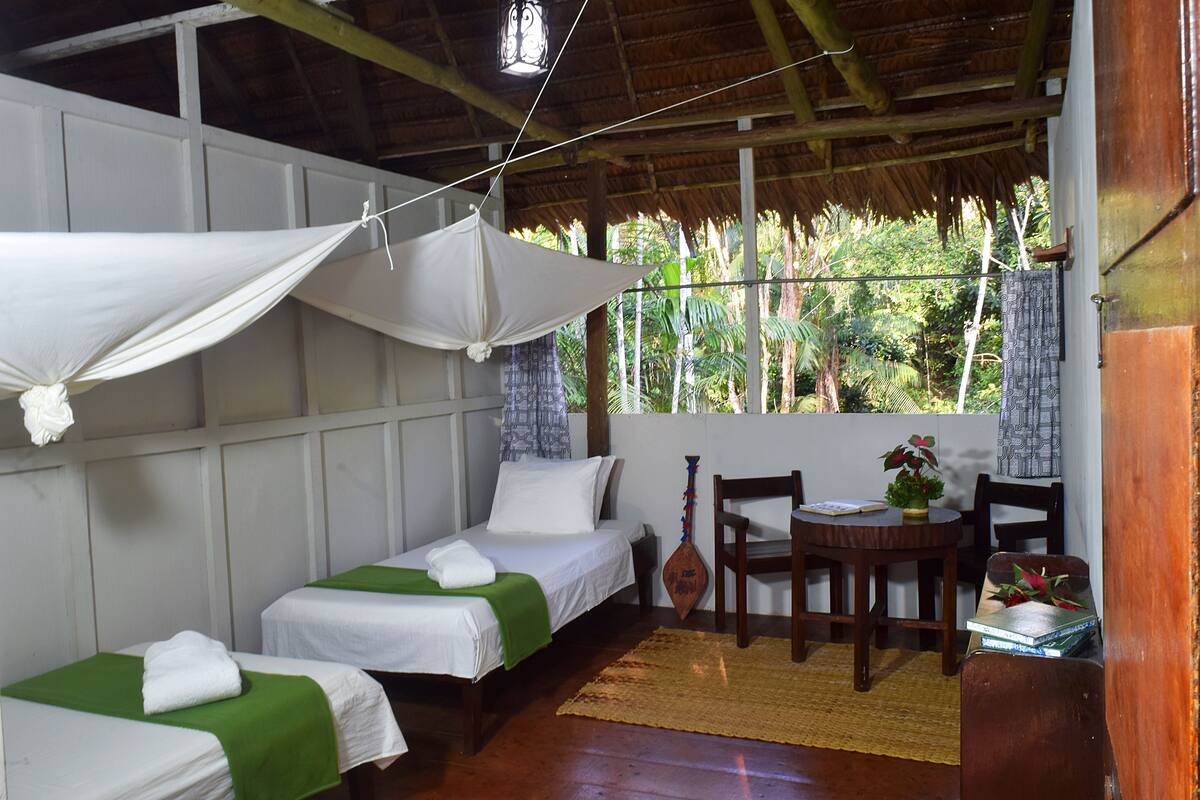 Una habitación con dos camas, una mesa de madera y una silla.