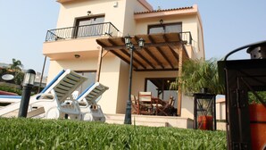 A two-story building with a balcony, outdoor seating, and a well-maintained lawn. - Vineland Holiday Villas (Pissouri)