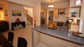 A modern kitchen with a central island, wooden cabinets, and a dining area with a dark wooden table and chairs.