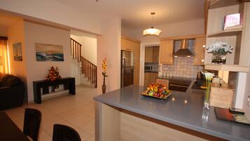 Una cocina moderna con una isla central, armarios de madera y un comedor con una mesa y sillas de madera oscura.