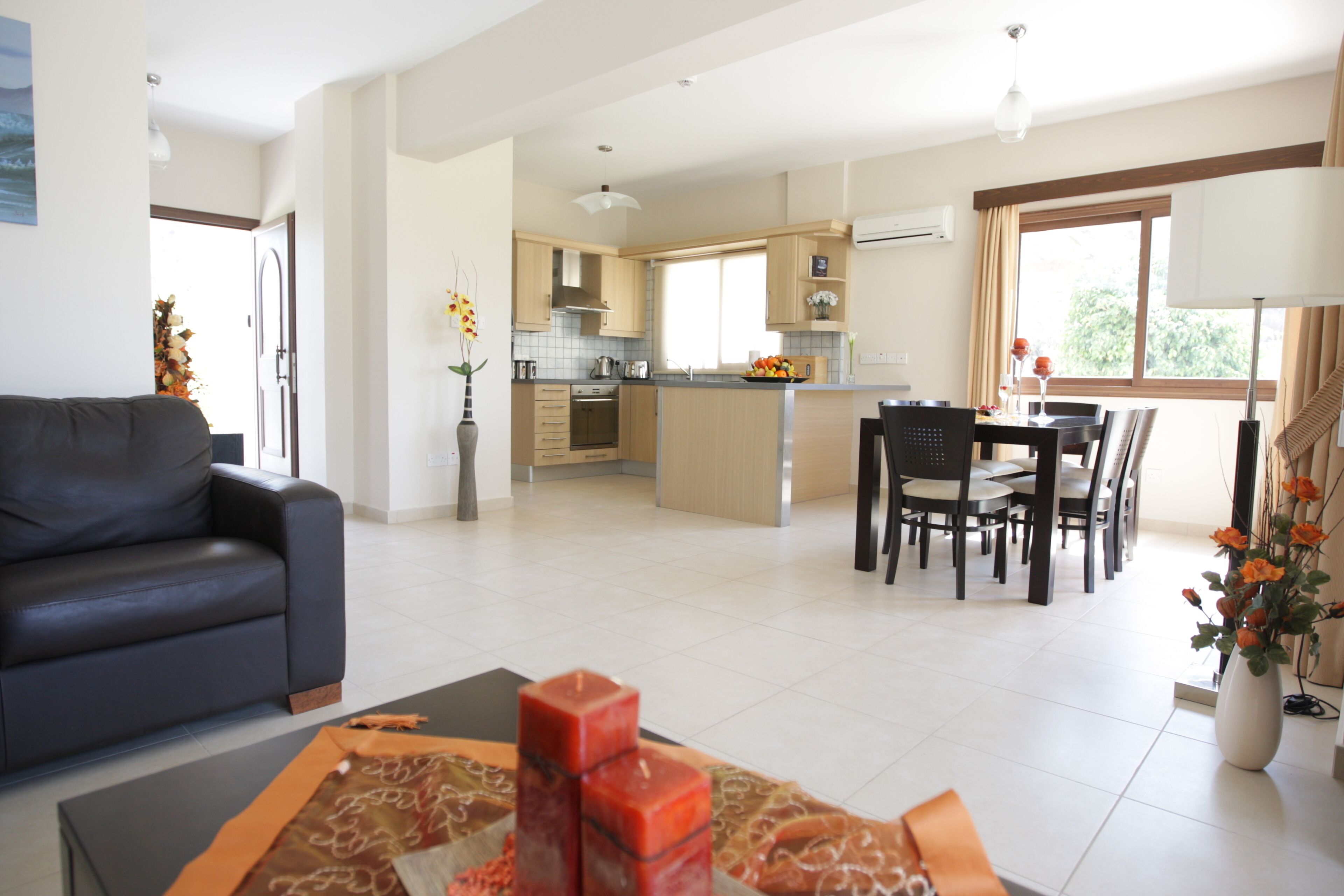 Una sala moderna con sofá, comedor con mesa y sillas, y cocina con armarios y electrodomésticos.