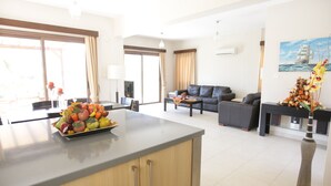 Amplia sala de estar con una isla grande, un conjunto de sofás y un comedor con fruteros.