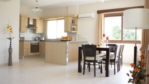 Una cocina moderna con comedor, que presenta armarios de madera, una isla central y un ventanal grande.