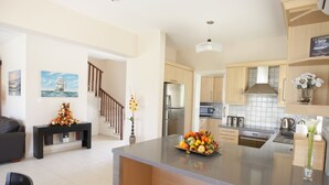 Una cocina moderna con una isla central, electrodomésticos de acero inoxidable y armarios de madera clara.