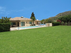 A house with a swimming pool, a patio with lounge chairs, and a well-maintained lawn. - Vineland Perigiali Villa (Pissouri)