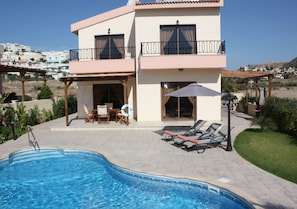 A two-story building with a swimming pool, outdoor seating, and a view of the surrounding area.