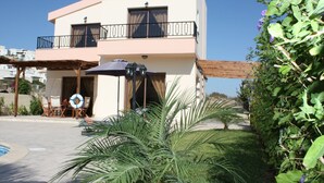 Un edificio de dos pisos con balcón, mobiliario exterior y piscina.