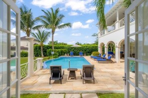 A pool area with lounge chairs, palm trees, and a clear sky. - Royal Westmoreland Mahogany Drive by Island Villas (Westmoreland)