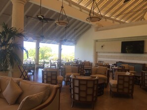 A spacious indoor area with multiple seating arrangements, including sofas and chairs, under a high ceiling with exposed beams and hanging lights. - Royal Westmoreland Mahogany Drive by Island Villas (Westmoreland)